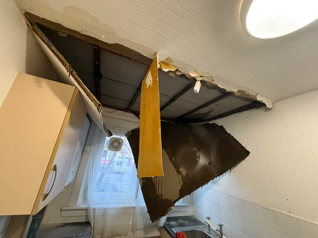 Collapsed kitchen ceiling with exposed joists and hanging boards, awaiting insurance reinstatement